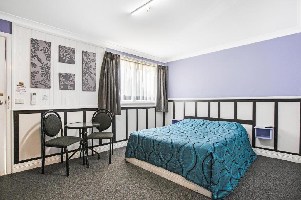a bedroom with a bed and a table and chairs at Tamworth Lodge Motel in Tamworth