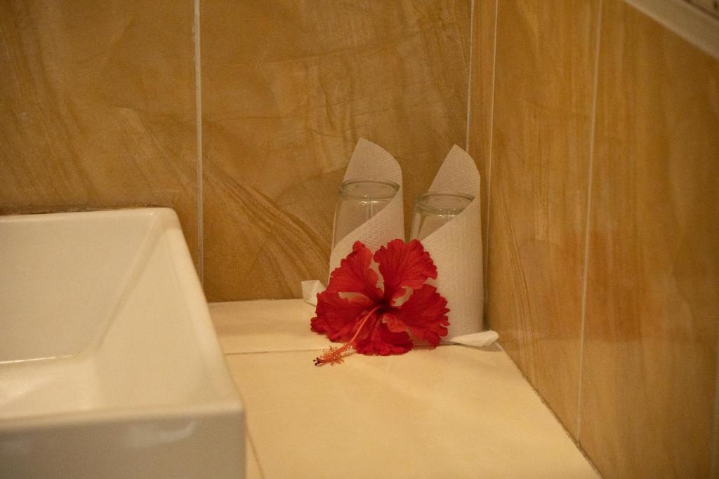 two wine glasses and a red flower sitting on a counter at Alam Terrace Cottages in Ubud
