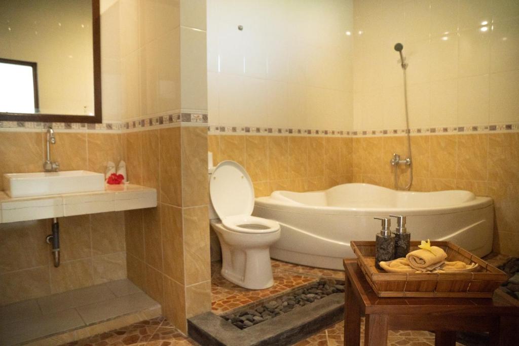 a bathroom with a tub and a toilet and a sink at Alam Terrace Cottages in Ubud