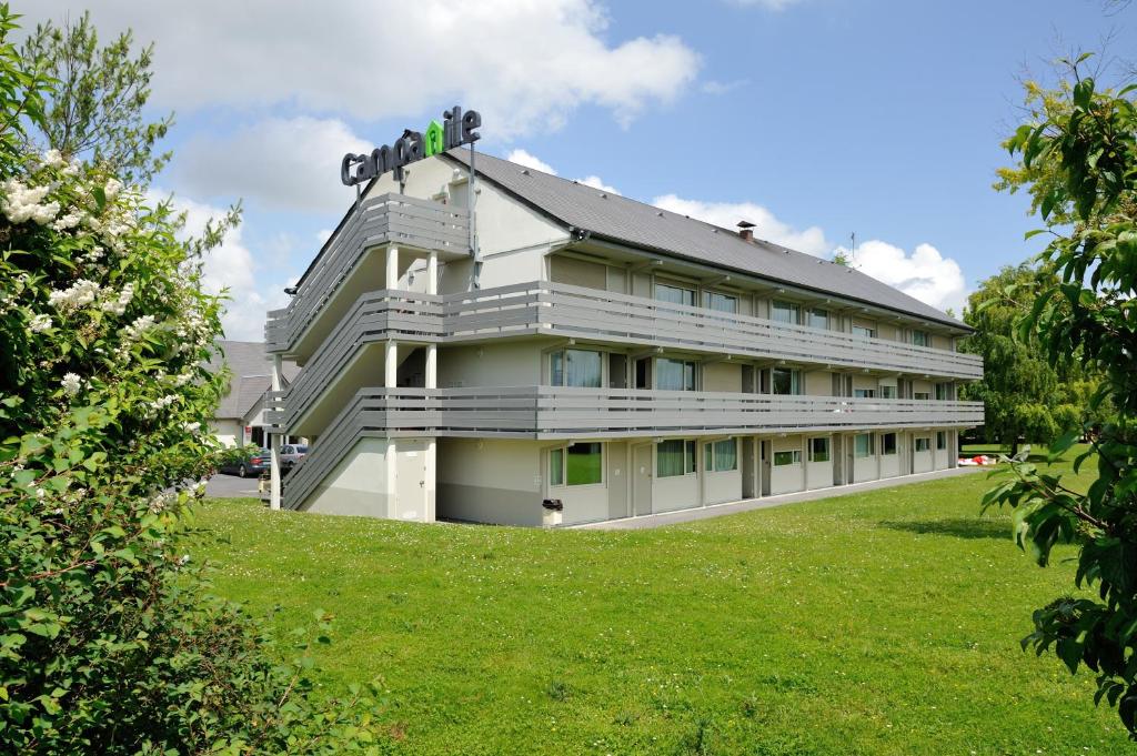 un grand bâtiment blanc avec une pelouse verte dans l'établissement Campanile Reims Est - Taissy, à Reims