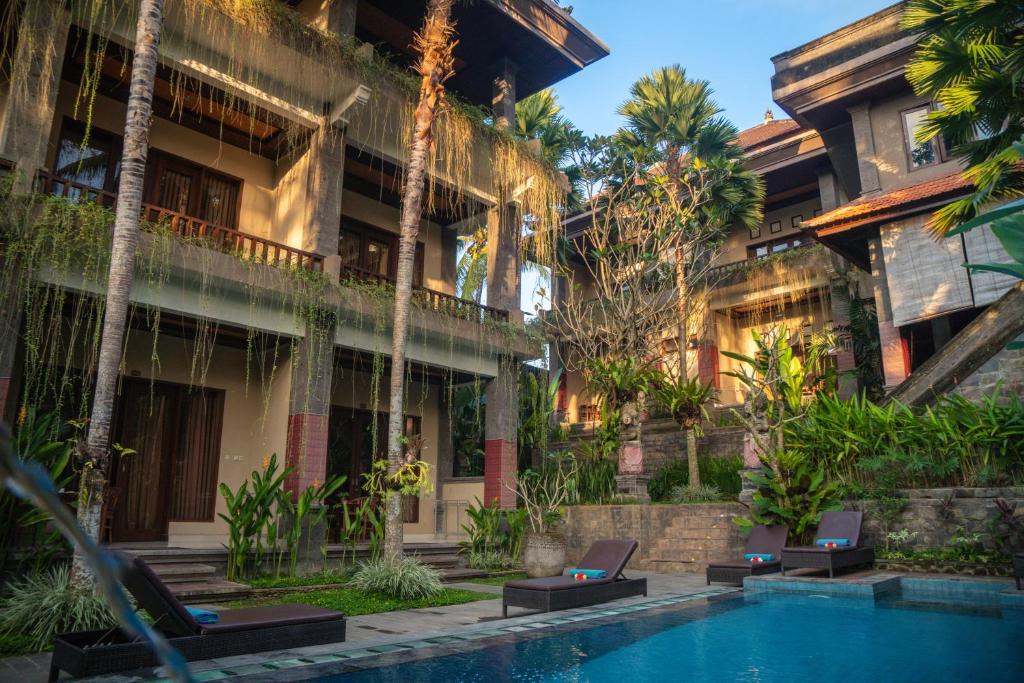 a hotel with a swimming pool in front of a building at Alam Terrace Cottages in Ubud