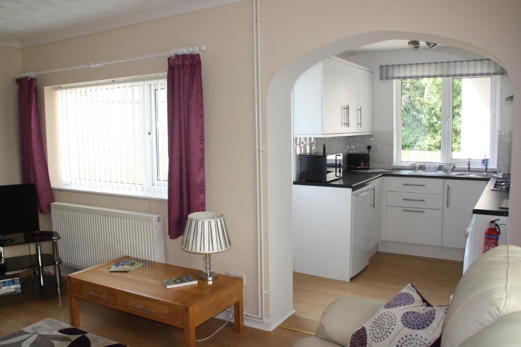 a living room with a table and a kitchen at Ortari@70 in Bishopston