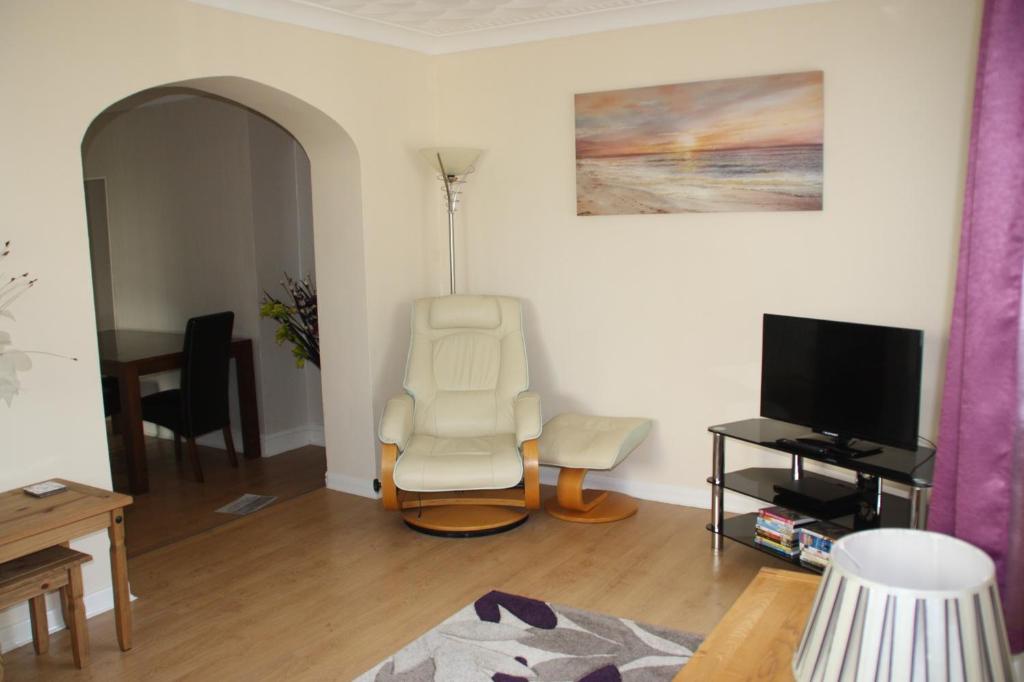 a living room with a chair and a television at Ortari@70 in Bishopston