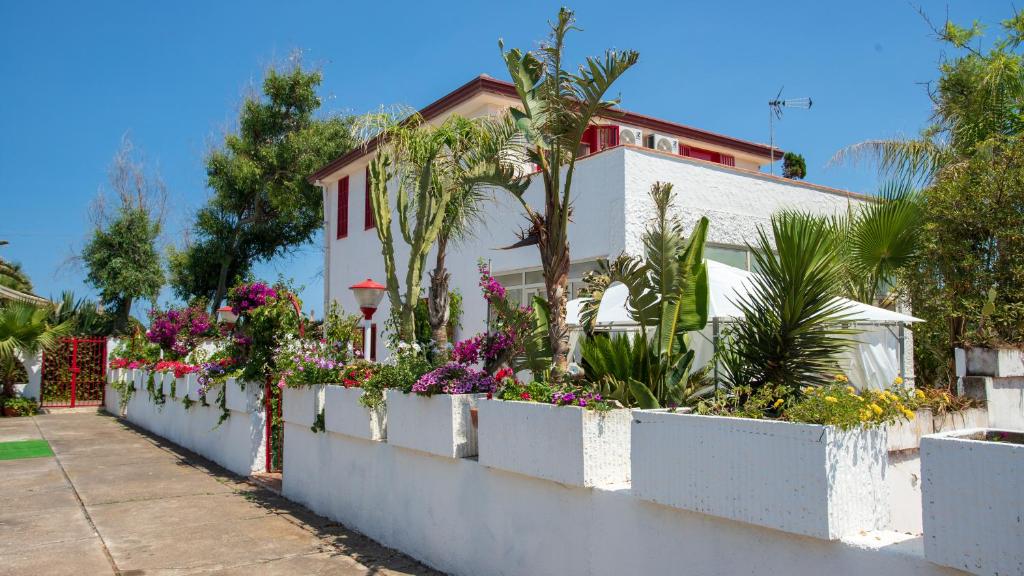 une clôture blanche avec des fleurs et des plantes devant une maison dans l'établissement Villa On the Sea Le Capannine, à Catane