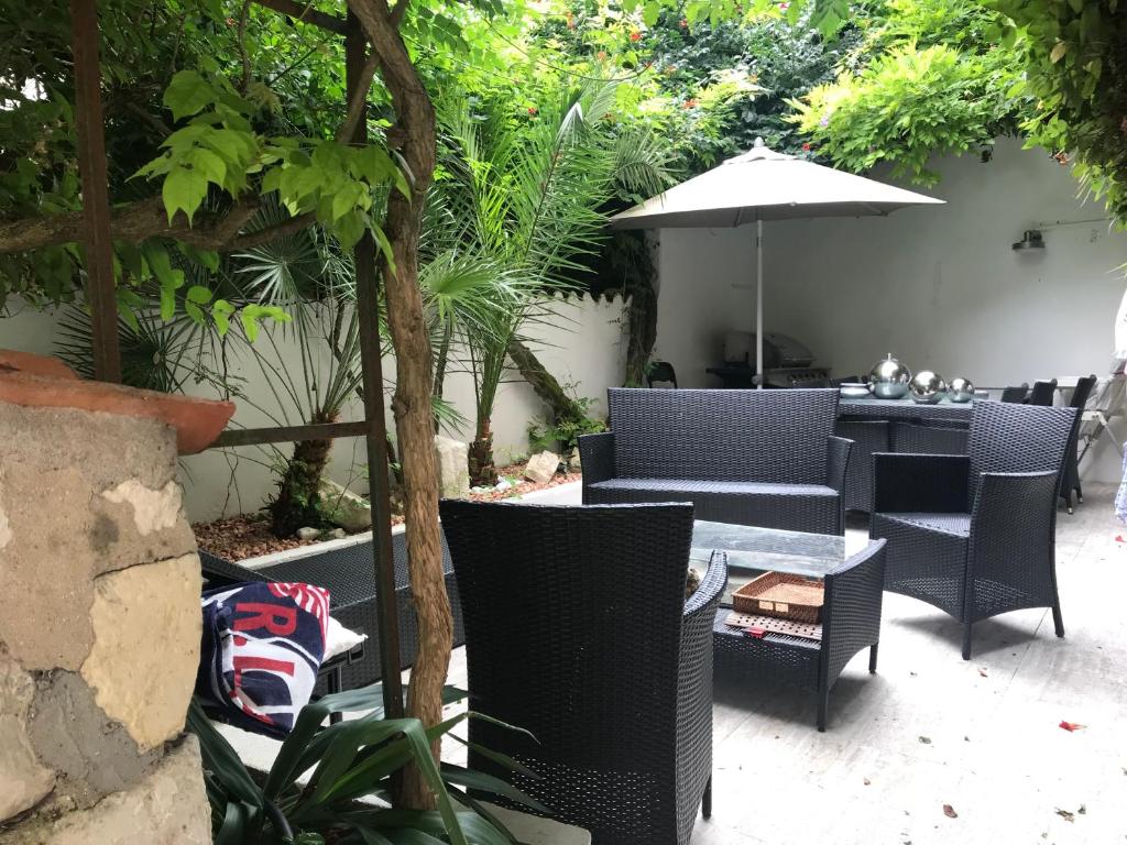 un patio con sillas y una mesa con sombrilla en Cloutiers26 en La Rochelle