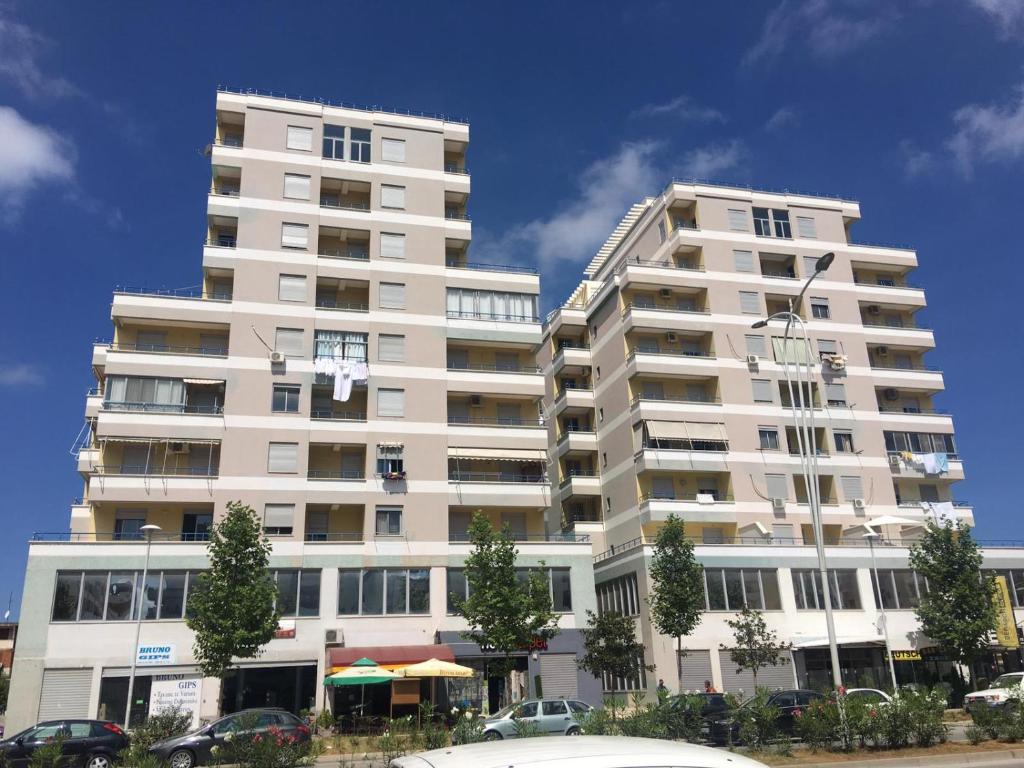 a tall white building with cars parked in front of it at The Place in Vlorë