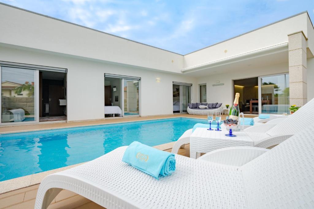uma villa com uma piscina e cadeiras brancas em BestVillas Apúlia Relax em Esposende