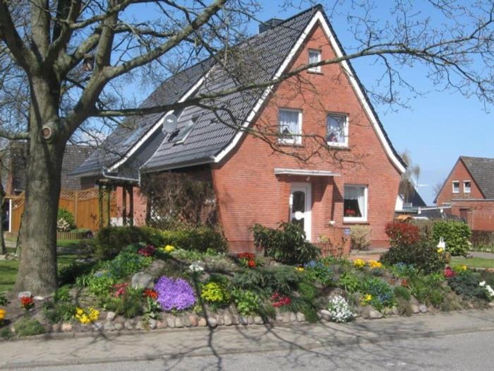 een rood bakstenen huis met bloemen ervoor bij Ferienwohnung Kremer in Cuxhaven