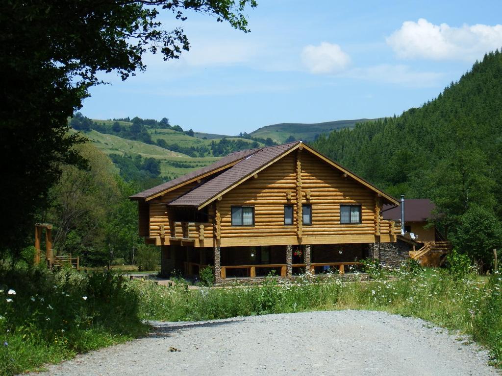 una cabaña de madera en las montañas en un camino de grava en Casa din Vale, en Săcuieu