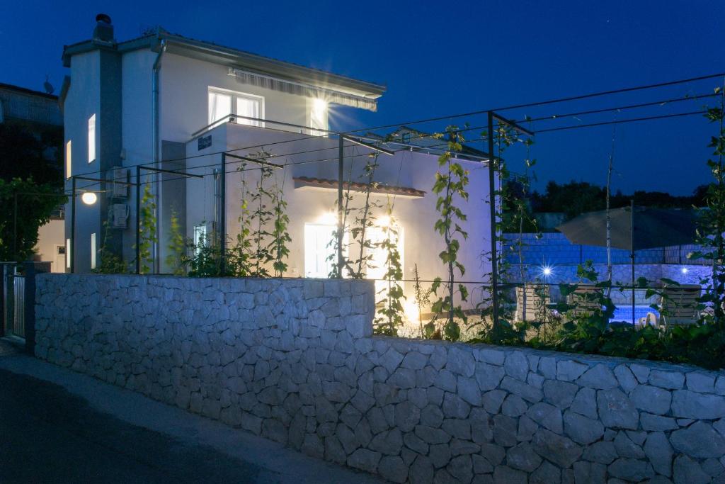 a white house with a stone wall at night at Villa Supuk in Vinišće