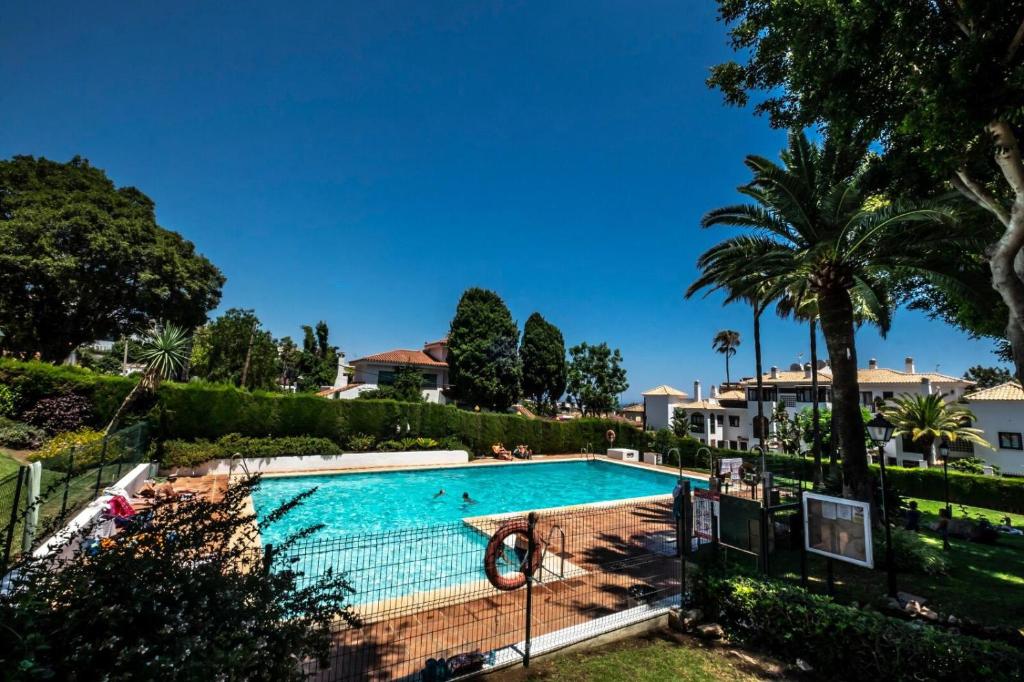 una piscina en una villa con palmeras en MalagaSuite Costa del Sol, en Torremolinos