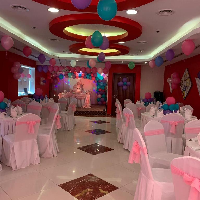 a banquet hall with white tables and chairs and balloons at Hala Inn Hotel Apartments - BAITHANS in Ajman 