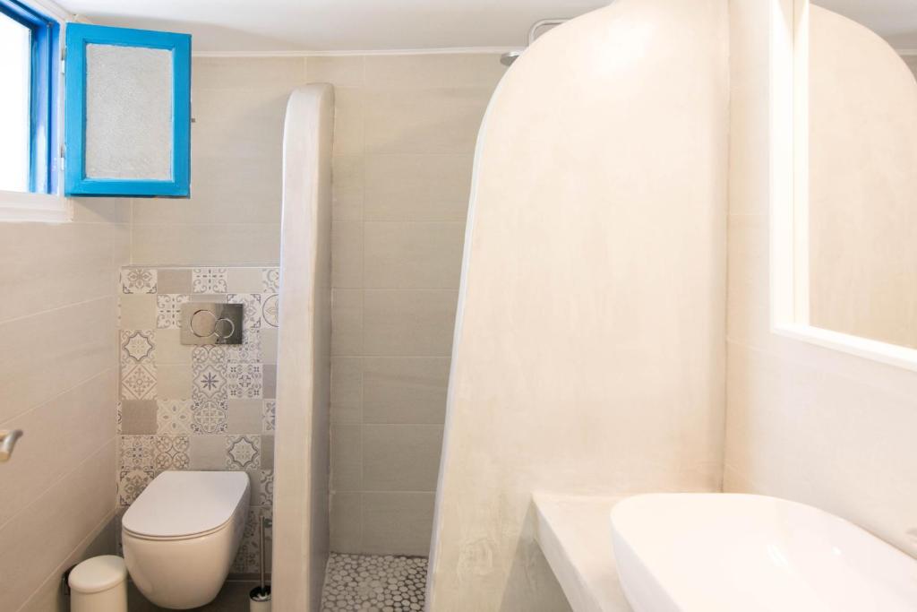 a bathroom with a white toilet and a sink at Santorini Villatzio Suites in Mesaria