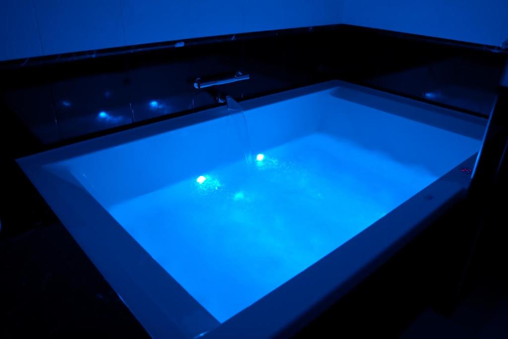 bañera con luces azules en una habitación en Hotel Maxim en Anzola dell'Emilia