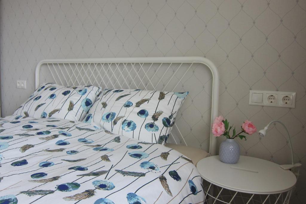 a bed with a blue floral bedspread and a table at Apartment Anna in Saldus