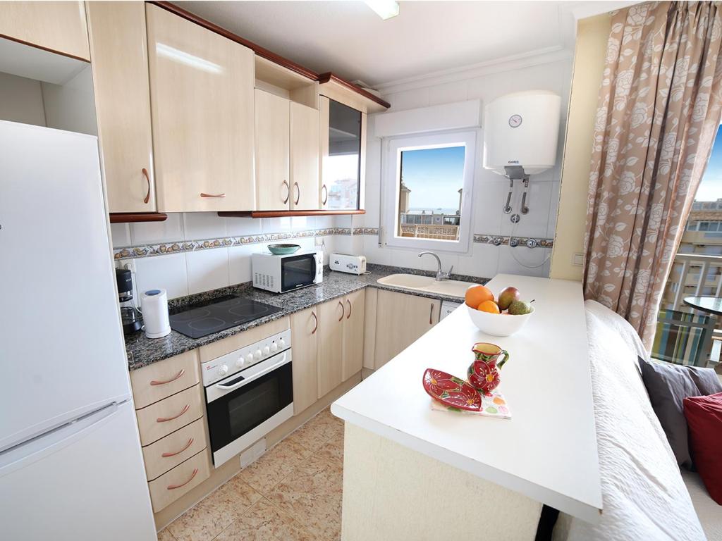 a kitchen with a counter with a bowl of fruit on it at Puerto y Playa Apartments La Manga in La Manga del Mar Menor