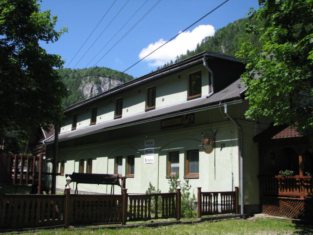 a green and white house with a wooden fence at Penzión Borovica in Stratená