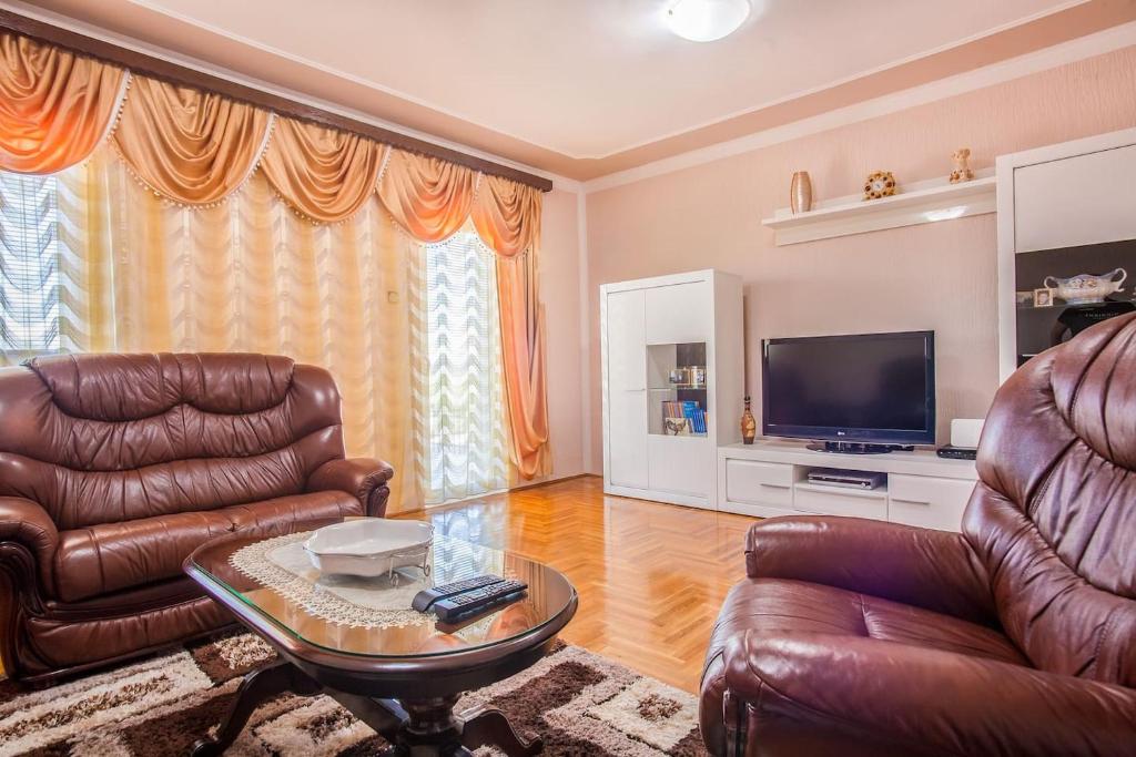 a living room with leather furniture and a flat screen tv at Luxury House Petrovic - Vranjina Skadar Lake in Podgorica