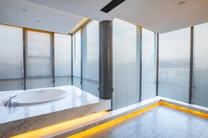 a large bathroom with a tub in front of windows at Metropolo Jinjiang Weihai Railway Station in Weihai