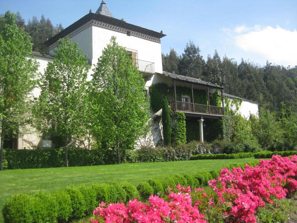 a house with a garden with pink flowers at Hotel Rural Palacio de Prelo in Boal