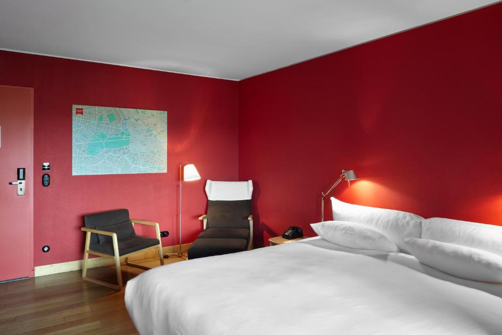 a bedroom with a red wall with a bed and a chair at Casa Camper Berlin in Berlin