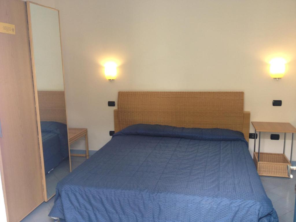 a bedroom with a blue bed and two lights on the wall at Hotel Aura in Vulcano