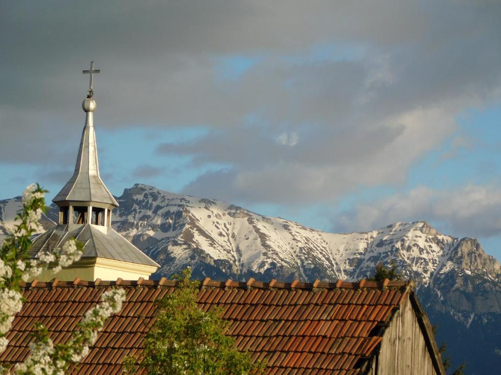 a church with a steeple and a snow covered mountain at Mountain Vista Suites in Zărneşti