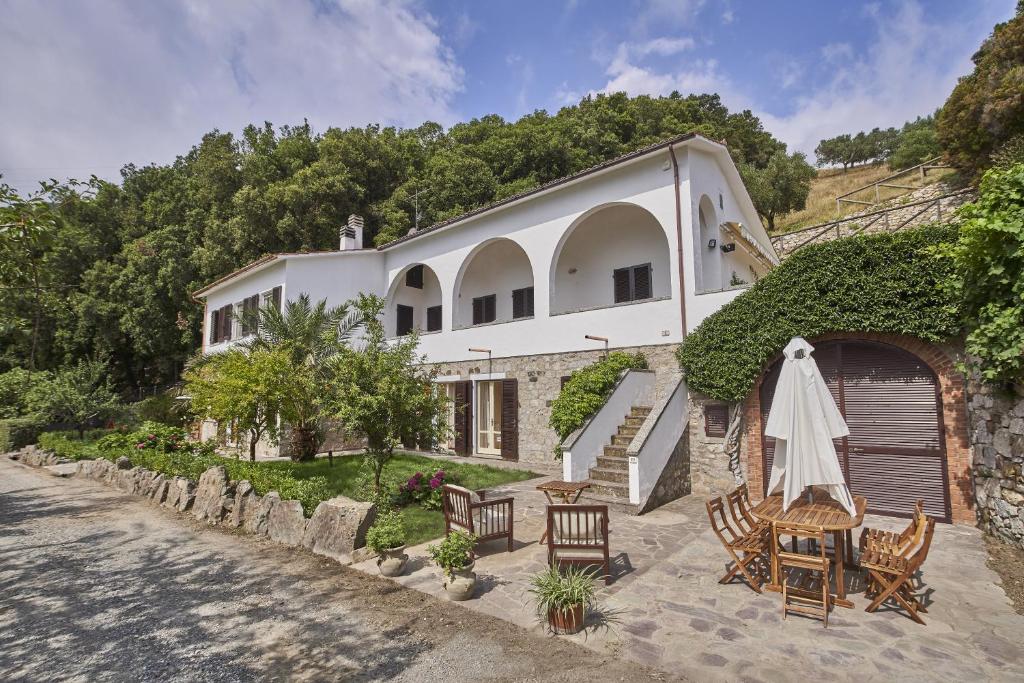 ein externer Blick auf ein Haus mit Stühlen und einem Regenschirm in der Unterkunft Marciana Hills Apartments in Marciana