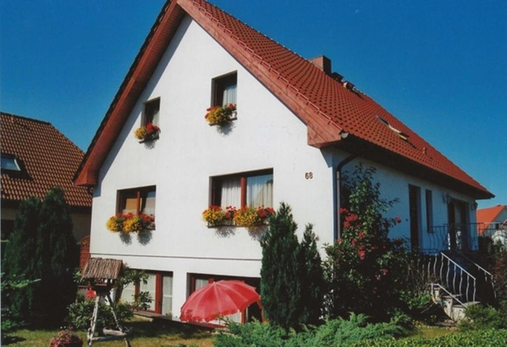 ein weißes Haus mit rotem Dach und einem roten Regenschirm in der Unterkunft Ferienunterkünfte Wießmann in Heringsdorf