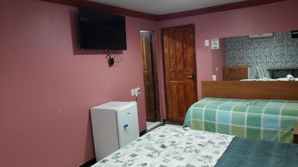 a bedroom with a bed and a television on the wall at Hotel Opção in Manaus