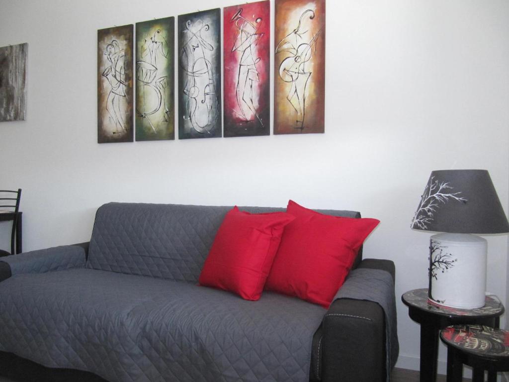 a living room with a couch with four paintings on the wall at Station Home in Sesto San Giovanni
