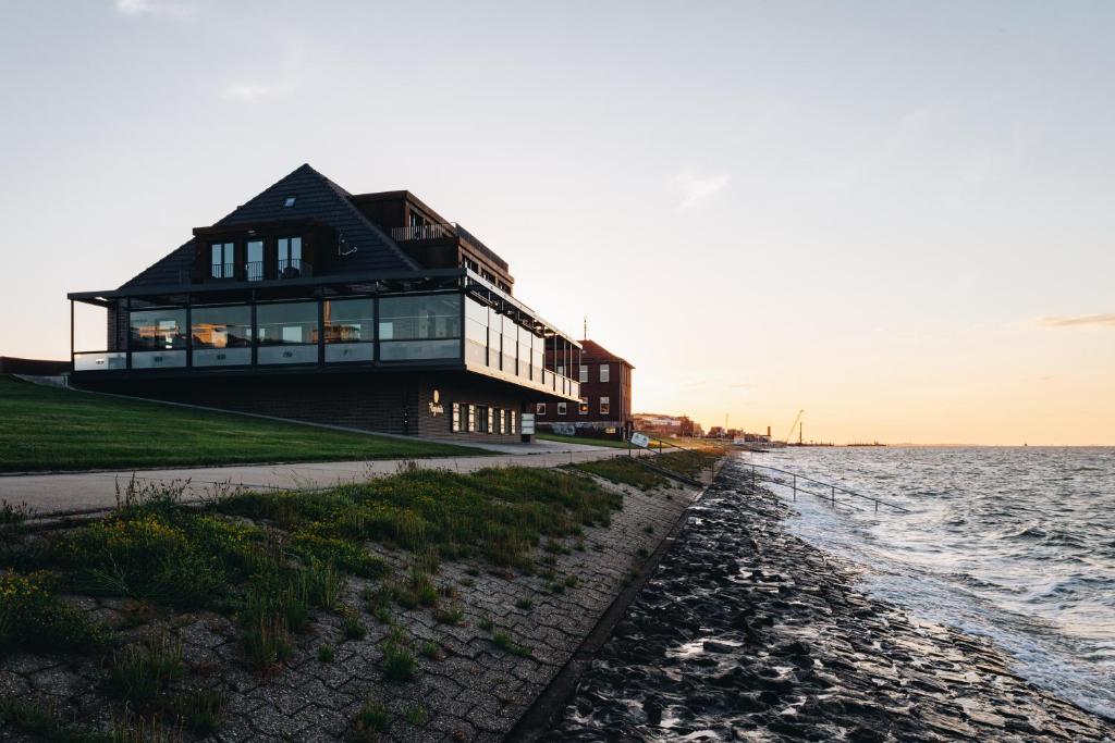 a house on the beach next to the water at Fliegerdeich Hotel & Restaurant in Wilhelmshaven