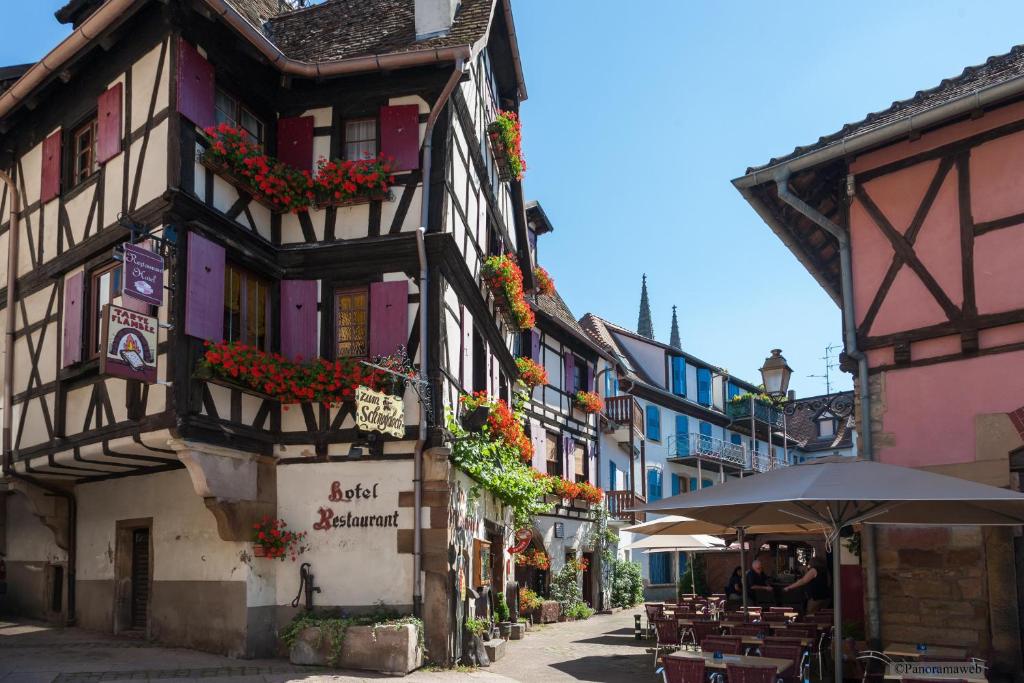 an old building with flowers on the side of a street at Hôtel Restaurant Zum Schnogaloch in Obernai