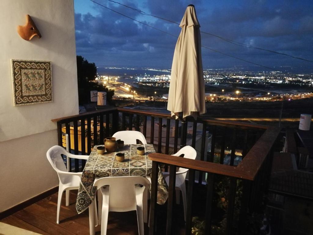 een balkon met een tafel en stoelen en een parasol bij The Potter's House overlooking the Bay of Haifa in Haifa