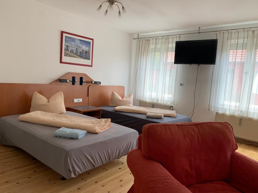 two beds in a room with a couch and a tv at Pension Scheffler in Potsdam