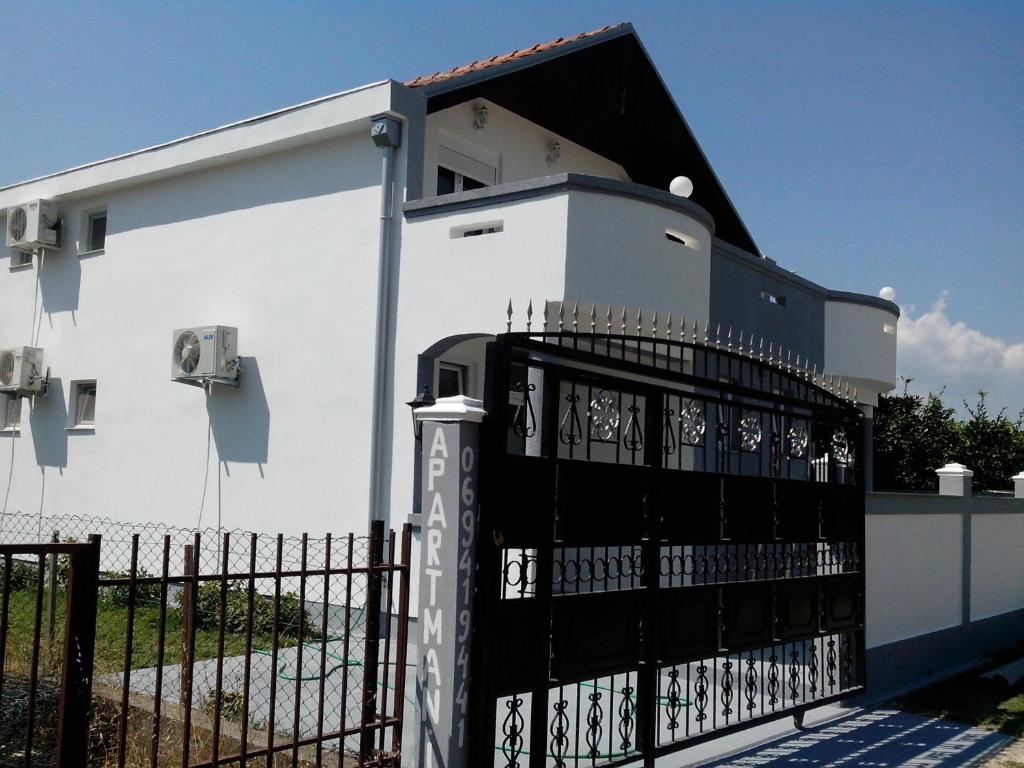 a white building with a black gate in front of it at Studios Velika Plaža in Ulcinj