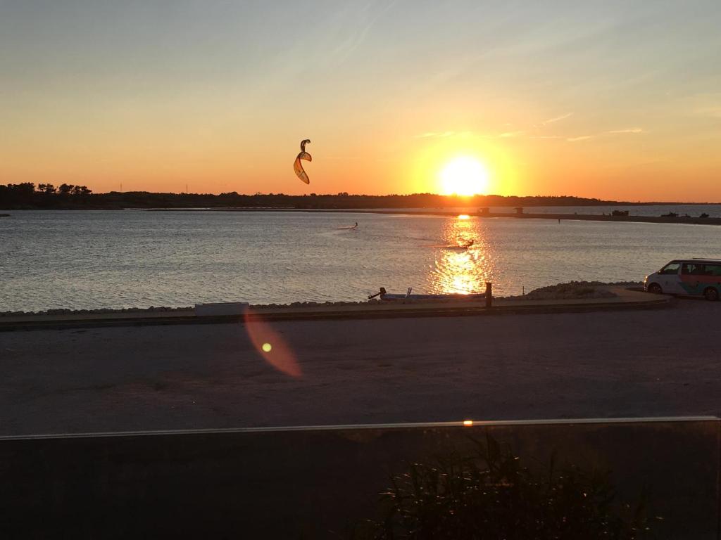 une personne volant un cerf-volant sur l'eau au coucher du soleil dans l'établissement Amazing View Apartments, à Nin