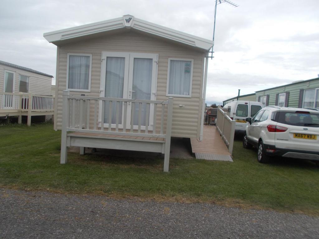 a tiny house with a porch and a car parked at ty gwyn in Abergele