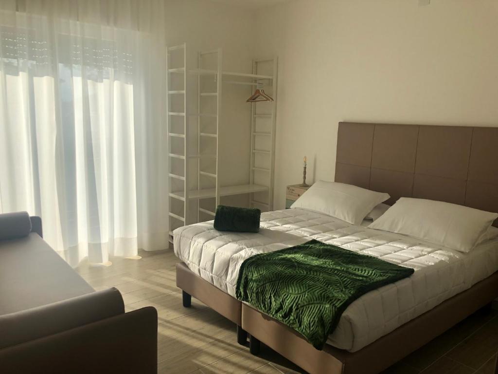 a bedroom with a bed with a green blanket on it at Sole&Luna - Rooms in Eraclea