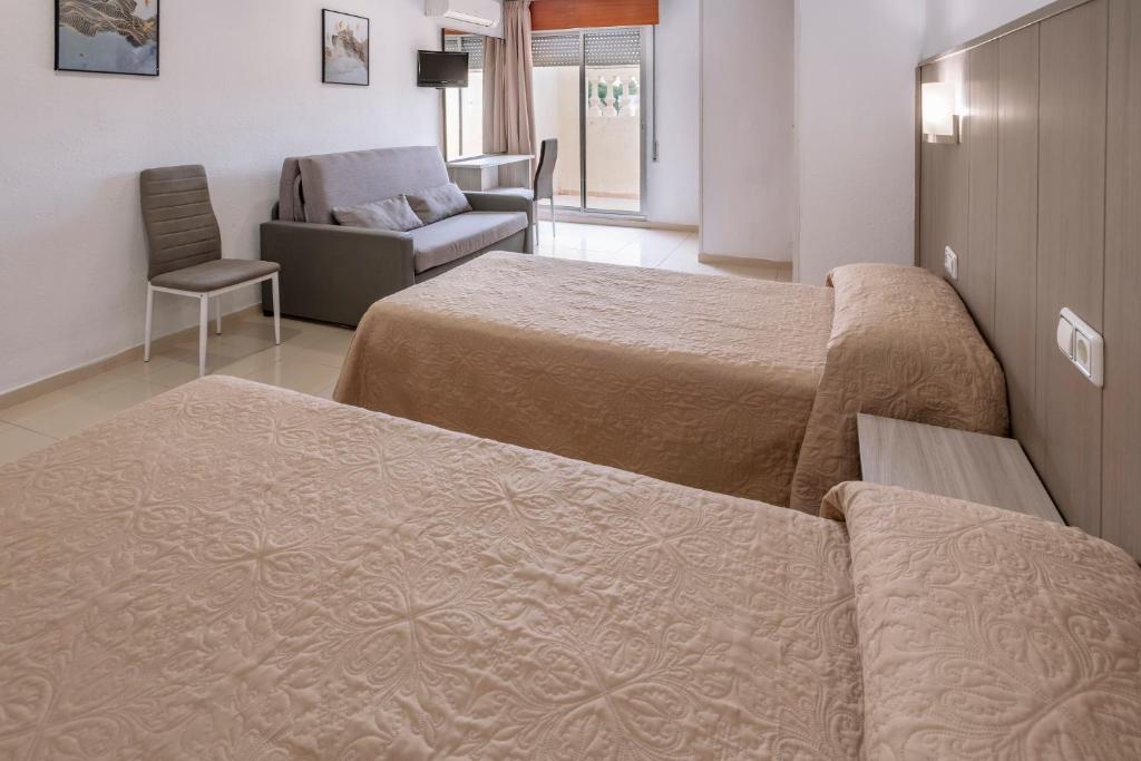 サロウにあるホテル ニザのベッド2台、ソファ、椅子が備わる客室です。
