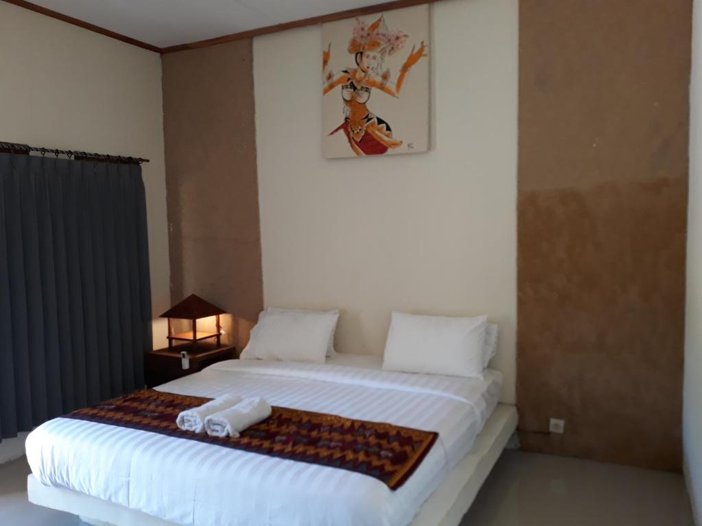 a bedroom with a large white bed with towels on it at Village Corner Homestay in Kuta Lombok
