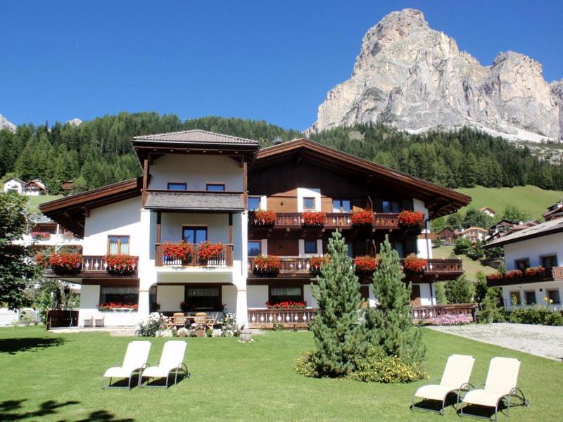 a building with chairs in front of it with a mountain at Garni Haus Tyrol in Corvara in Badia