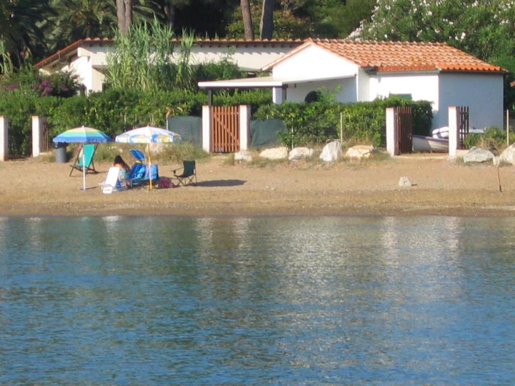 a couple of people sitting on a beach with umbrellas at casina mare sulla spiaggia in Capoliveri