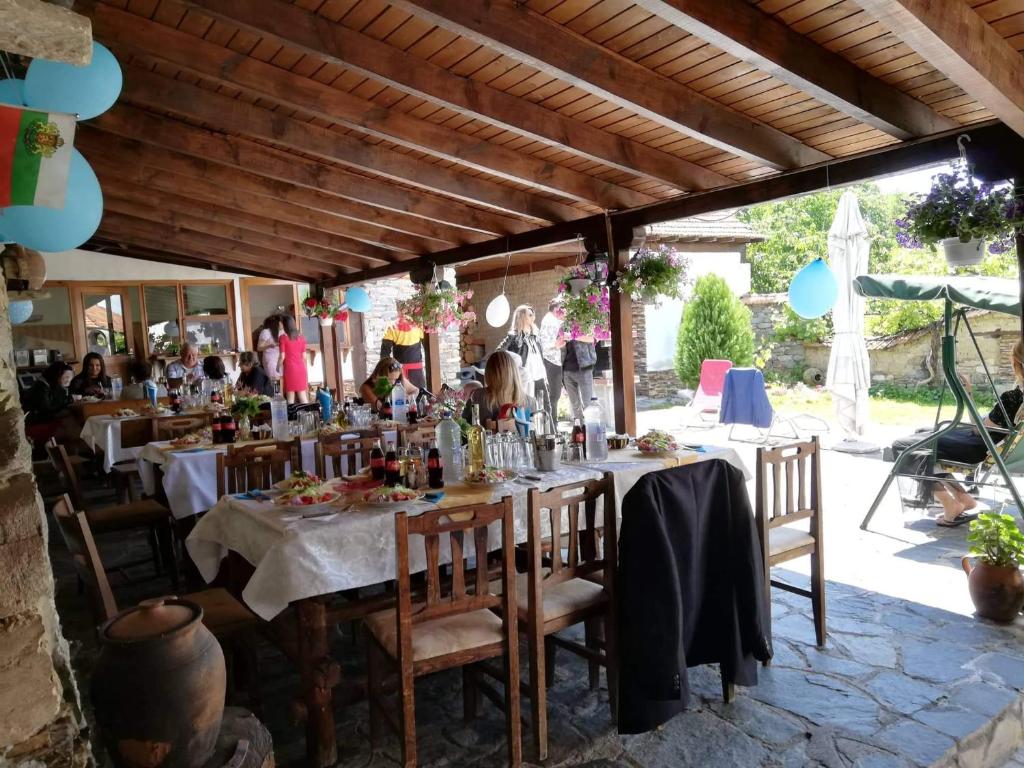 a restaurant with tables and chairs with people in the background at Guest House Popov in Marchevo