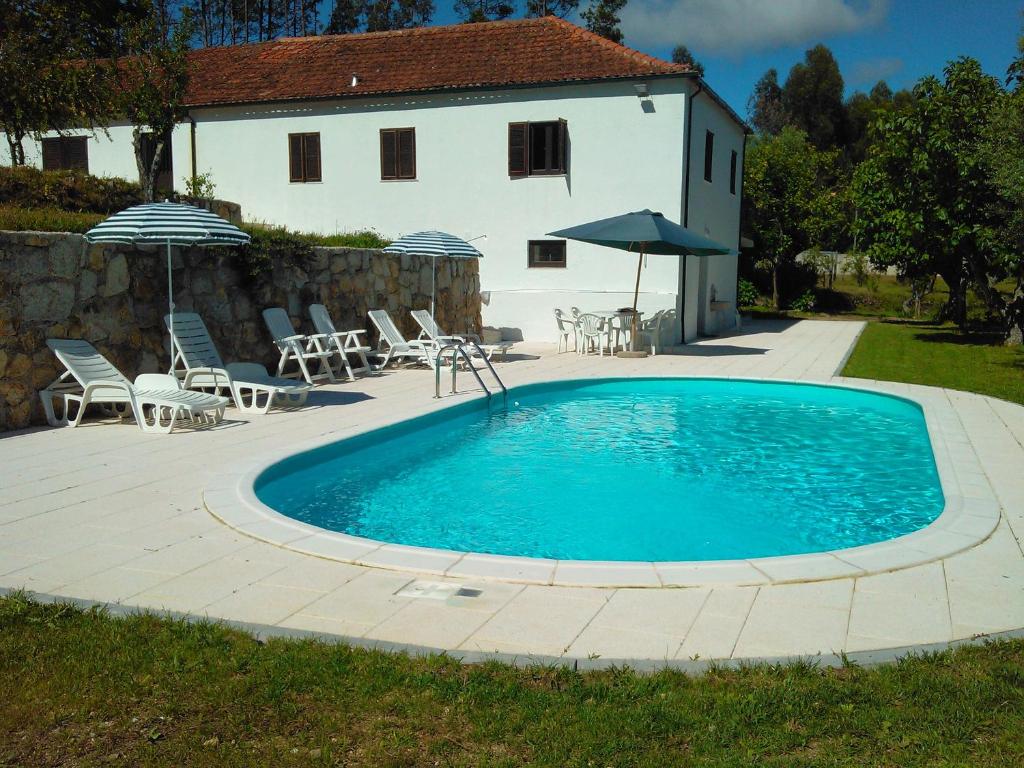 a pool with chairs and umbrellas next to a house at Casa Do Fiscal in Barroselas