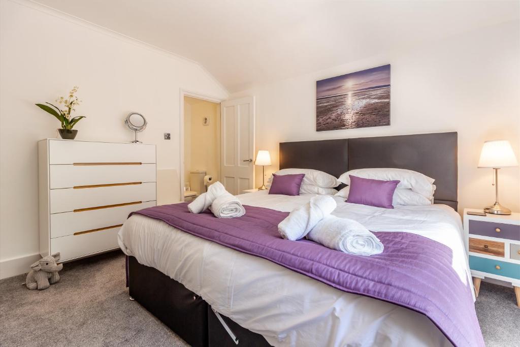 um quarto com uma cama grande e lençóis roxos em Guest Homes - Farningham Residence em Caterham