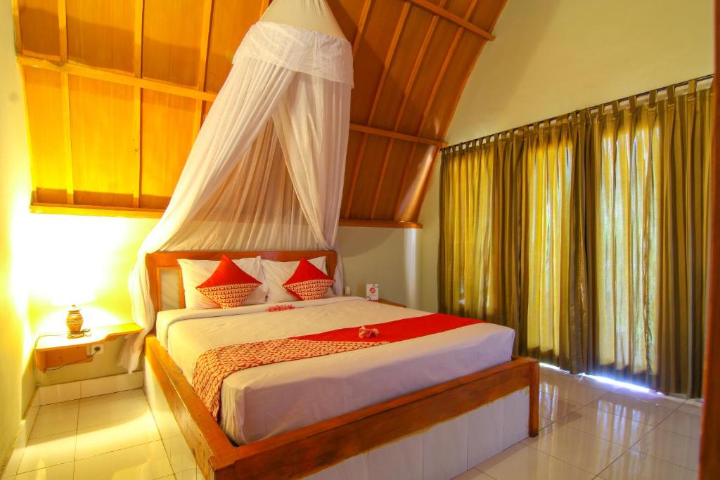 a bedroom with a bed with a canopy at Yoland Guesthouse in Gili Islands