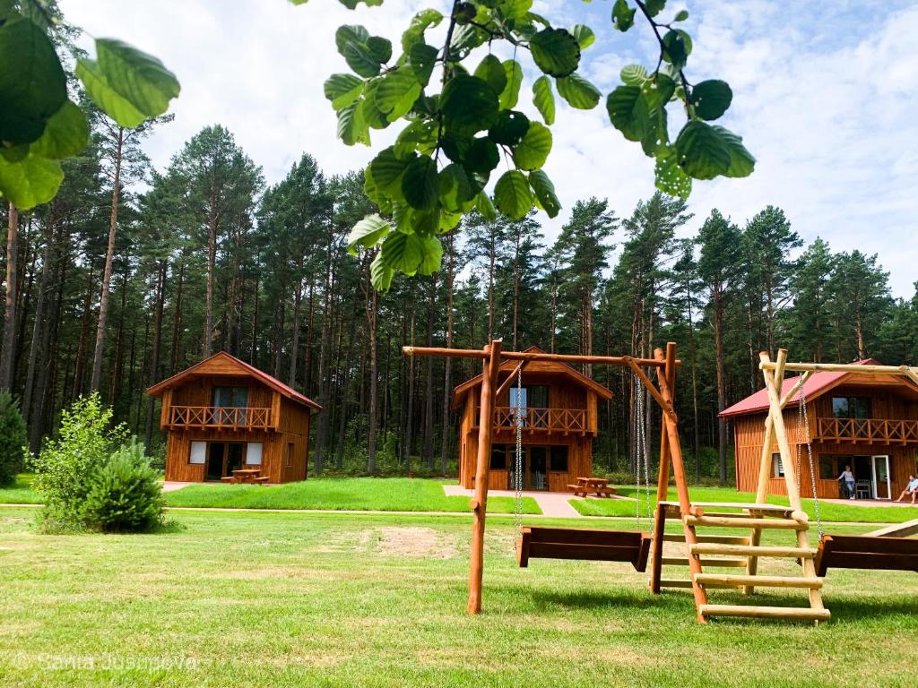 a playground in front of two log cabins at Brīvdienu māja VILCIŅI in Bernāti