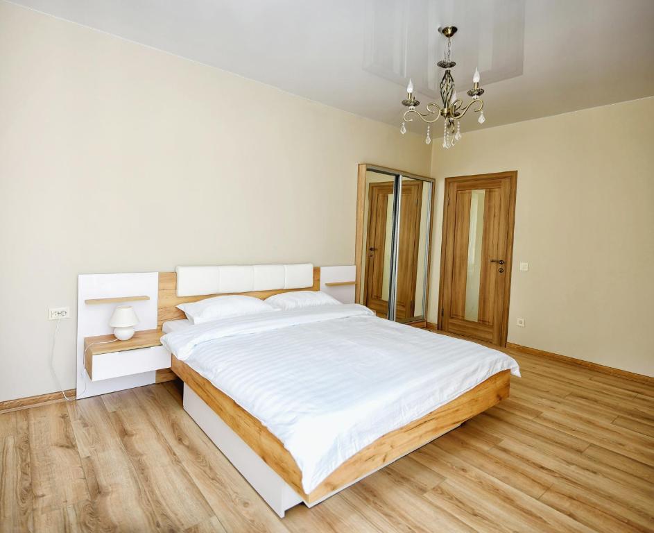 a white bedroom with a large bed and a chandelier at Apart Reserve Sloboda Klassik in Ivano-Frankivsk