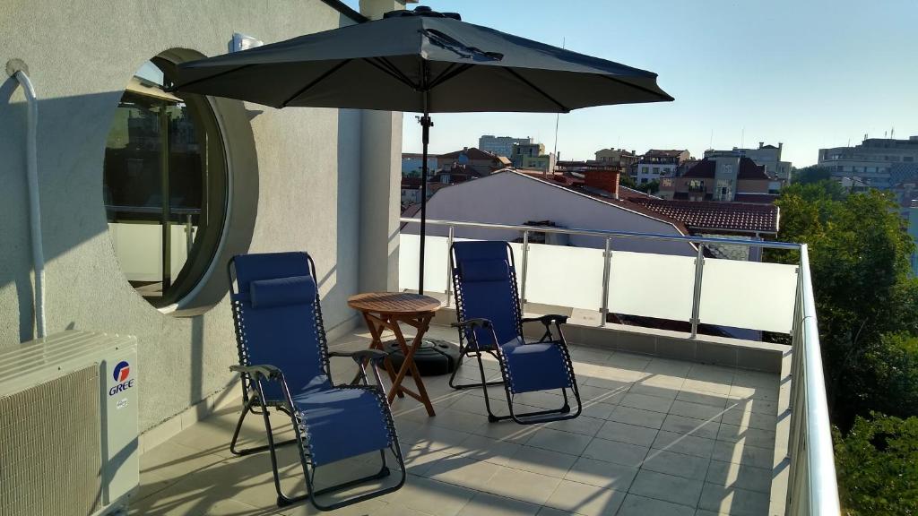 een patio met een tafel en stoelen en een parasol bij Sky Blue Danube Apartment Ruse in Ruse